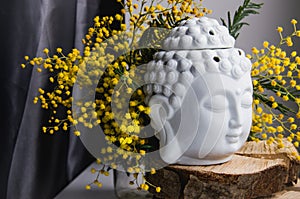 Spiritual ritual meditation face of Buddha on wood, home decor, mimosa yellow spring flowers