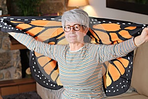 Spiritual senior woman holding dreamy butterfly wings