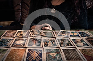 Spiritual wicca witch reading occult mystic old tarot cards laying on table for a magical pagan ritual psychic destiny reading