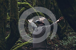 Spiritual zenlike nature love people. One man with closed eyes and outstretching arms in the nature forest green trees scenic photo