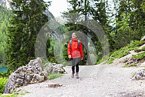 Spiritually strong woman hiking alone in the mountains in red raincoat