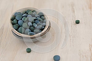 Spirulina algae green in tablets in round ceramic cups on a light wooden shabby background..Dietary supplements.Super
