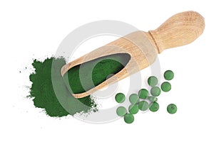 Spirulina algae powder and pills in wooden scoop isolated on white background. Top view