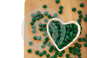 Spirulina algae tablets cup on a wooden board on a white background.Vitamins and dietary supplements.Super food .Food