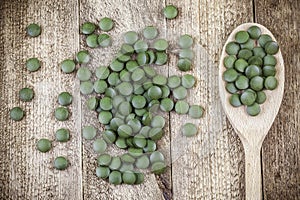 Spirulina,chlorella supplement pills in wooden spoon on table