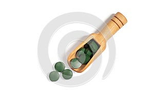Spirulina green pills in a wooden spoon isolated on a white background. Chlorella tablets. View from above