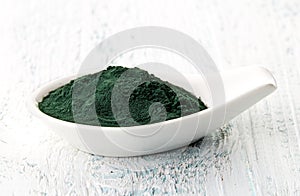 Spirulina powder in white porcelain spoon