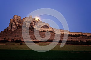 Spis Zipser Castle above valley at sunset with moon