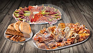 Spit Roasted Pork Meat and Appetizer Dish Meze with Pita Flatbread Loaves and Sliced Baguette on Rustic Old Pinewood Table