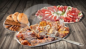 Spit Roasted Pork Meat and Appetizer Dish Meze with Pita Flatbread Loaves and Sliced Baguette on Rustic Old Pinewood Table