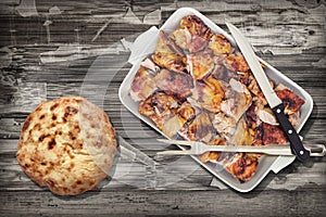Spit Roasted Pork Meat Slices in Oblong Casserole Pan with Pita Bread Loaf Served on Rustic Weathered Grunge Wooden Vignette Backd