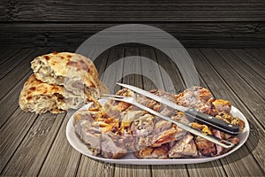 Spit Roasted Pork Meat Slices in Oval Porcelain Tray with Pita Bread Loaf Set on Rustic Weathered Grunge Wooden Vignette Backdrop