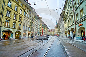 Spitalgasse street with colorful Pfeiferbrunnen fountainn and typical Bernese houses with arcades, on March 31 in Bern,