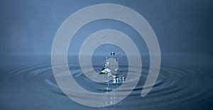 Splash and bubbles in cold fresh water with ripples in concentric circles