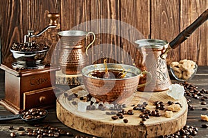 Splash Coffee in copper cup, vintage coffee grinder and jug with milk, lump sugar on wooden background