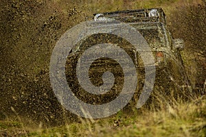 Splash of dirt under SUV on countryside road. Cross country rallying or rally raid on autumn field. Off road car takes