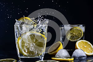 Splash Gin and tonic cocktail with lemon slices Ice cube falls into water with lemon Copy space, lemonade