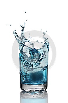 Splash in glass of blue alcoholic cocktail drink with ice cube