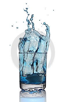 Splash in glass of blue alcoholic cocktail drink with ice cube