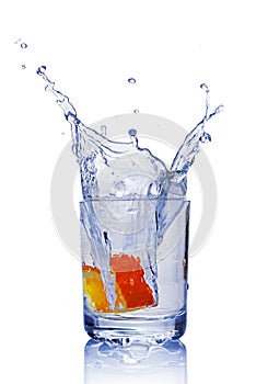 Splash in glass of blue water with orange slice