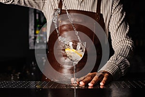 Splash in a glass with lemon barman on background