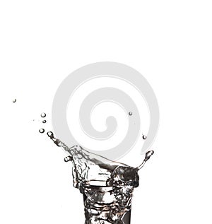 Splash in a glass on white isolated background. Vodka on an old wooden table as detailed close-up shot, Hand over glass