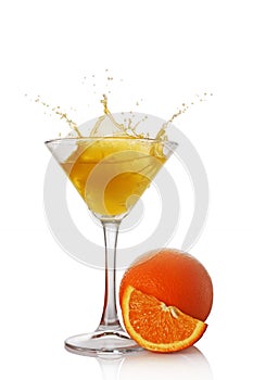 Splash in glass of yellow alcoholic cocktail drink with orange