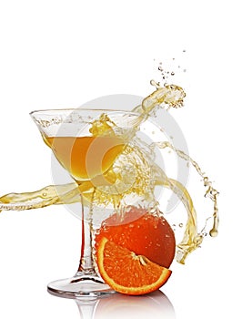 Splash in glass of yellow alcoholic cocktail drink with orange