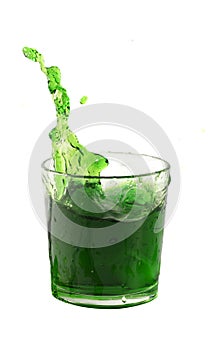 Splash from ice cube in a glass of green water or drink