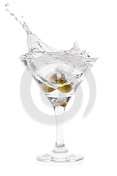 Splash of martini with olives in cocktail transparent glass on t