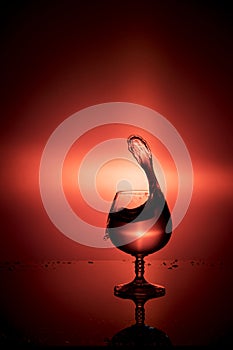 Splash of water in wine glass on a red background