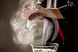 Splash white flour on black background and hands