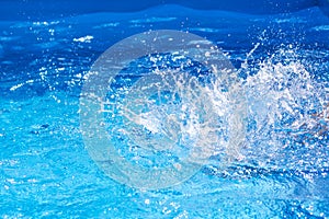 Splashes of clear blue fresh water in pool, air bubbles, water drops, sea wave on blue background with sunny reflections