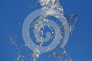 Splashes of flying water from the fountain against the blue sky