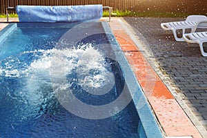 Splashes in the outdoor swimming pool near the white deck chairs. Recreation area at the resort, ticket to the hotel, sauna