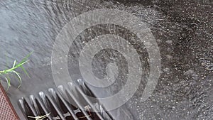 Splashes of raindrops falling into sidewalk with metal drainage through sewer drain