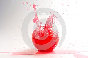 Splashes of red liquid in a glass globular vase