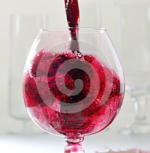 Splashes of red whine while filling a glass