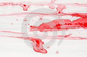 Splashes and stripes of scarlet red liquid paint on white as bright art abstract texture, background.