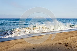 Splashing breaking wave on sandy shore with backwash and horizon photo