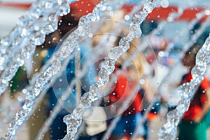 Fountain streams with frozen water drops on a blurry background of walking people