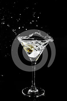 Splashing olive into a martini glass