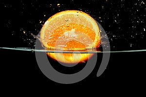 Splashing orange fruit into water