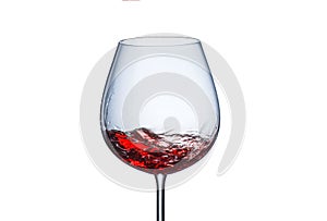 Splashing red wine in a glass goblet on white background