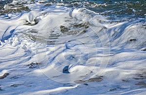 Splashing Sea waves with foam  and  spray; closeup photo. Sea foam.