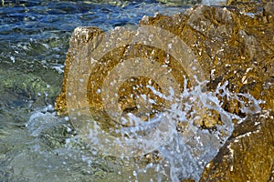Splashing water against the background of stone and sea, water drops