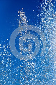 Splashing water from a fountain against the blue sky