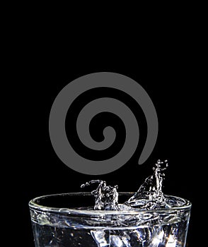 splashing water into glass on black background