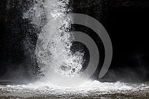 Splashing water from powerful waterfall with dark background