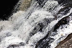 Splashing water on rocky slope of waterfall inside tropical rainforest